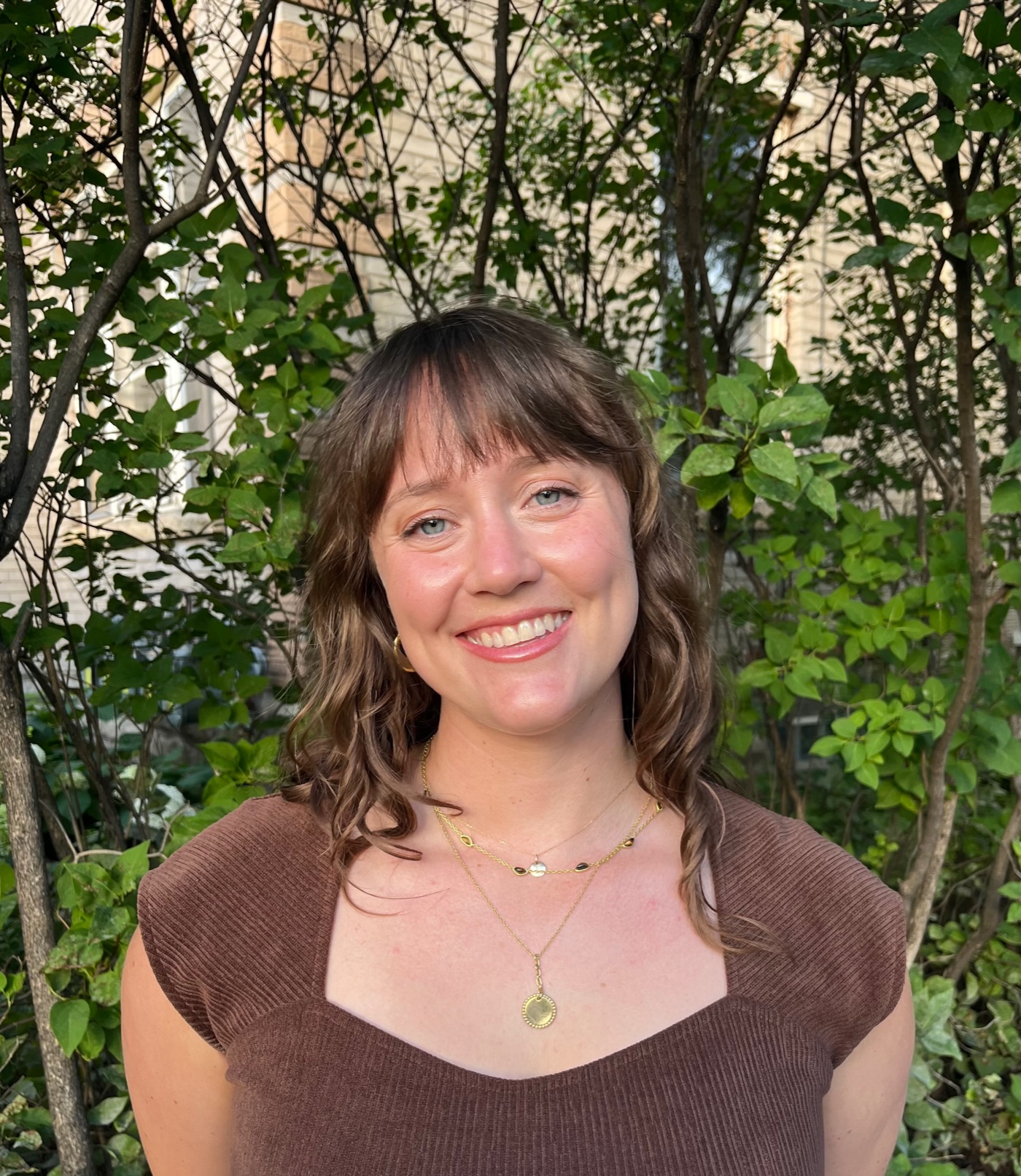 Photograph of Lucy Rea from the chest up in front of foliage.
