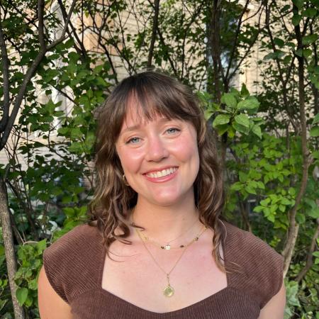 Photograph of Lucy Rea from the chest up in front of foliage.